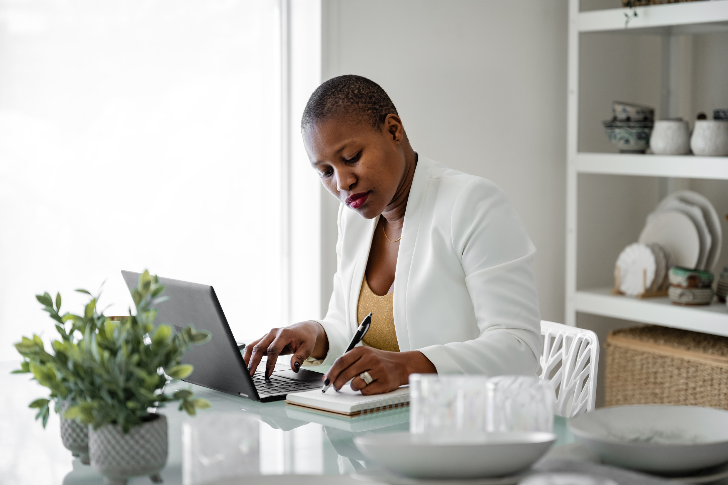Woman Writing on a Notebook and Typing on a Laptop